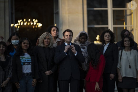 Le président de la République française, Emmanuel Macron et sa femme la Première Dame, Brigitte Macron posent pour une photo de groupe avec les premières lauréates de l'Initiative Marianne pour les défenseurs des droits de l'homme à la suite d'une cérémonie de remise de prix dans le cadre de la journée internationale de la femme, au palais de l'Elysée à Paris, France, le 8 mars 2022.