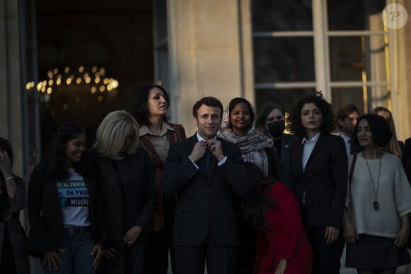 Le président de la République française, Emmanuel Macron et sa femme la Première Dame, Brigitte Macron posent pour une photo de groupe avec les premières lauréates de l'Initiative Marianne pour les défenseurs des droits de l'homme à la suite d'une cérémonie de remise de prix dans le cadre de la journée internationale de la femme, au palais de l'Elysée à Paris, France, le 8 mars 2022.