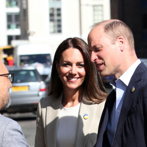 Le prince William, duc de Cambridge, et Catherine (Kate) Middleton, duchesse de Cambridge, visitent le comité d'urgence de Londres, à la rencontre de bénévoles de retour de leur mission humanitaire en Ukraine, le 21 avril 2022. En guise de soutien, le couple princier porte un badge aux couleurs du drapeau ukrainien. 