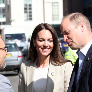 Le prince William, duc de Cambridge, et Catherine (Kate) Middleton, duchesse de Cambridge, visitent le comité d'urgence de Londres, à la rencontre de bénévoles de retour de leur mission humanitaire en Ukraine, le 21 avril 2022. En guise de soutien, le couple princier porte un badge aux couleurs du drapeau ukrainien. 