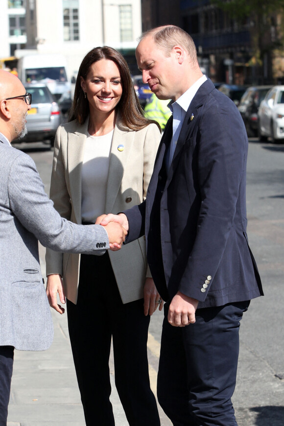 Le prince William, duc de Cambridge, et Catherine (Kate) Middleton, duchesse de Cambridge, visitent le comité d'urgence de Londres, à la rencontre de bénévoles de retour de leur mission humanitaire en Ukraine, le 21 avril 2022. En guise de soutien, le couple princier porte un badge aux couleurs du drapeau ukrainien. 