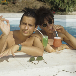 En France, à Saint-Tropez, Laurent Gerra et Virginie Lemoine en vacances au Mas de Chastelas, dans la piscine le 10 août 1995.