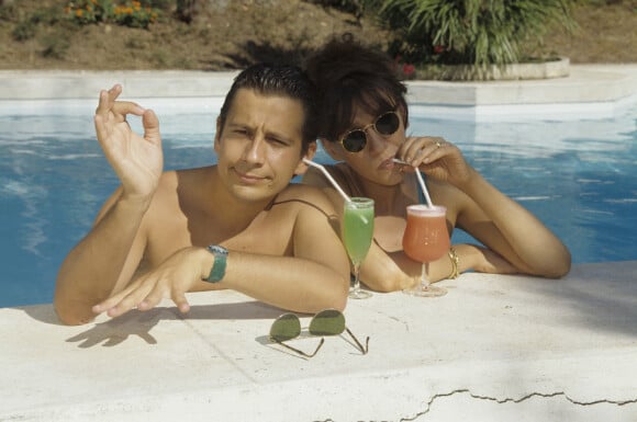 En France, à Saint-Tropez, Laurent Gerra et Virginie Lemoine en vacances au Mas de Chastelas, dans la piscine le 10 août 1995.