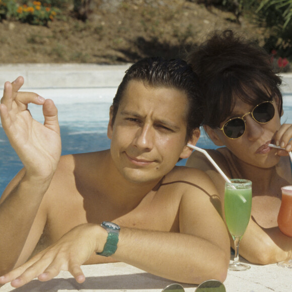 En France, à Saint-Tropez, Laurent Gerra et Virginie Lemoine en vacances au Mas de Chastelas, dans la piscine le 10 août 1995.