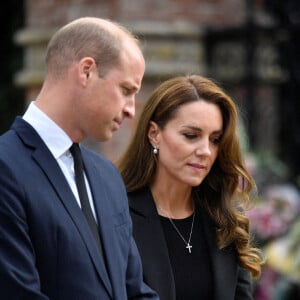 Le prince William, prince de Galles, et Catherine (Kate) Middleton, princesse de Galles regardent les hommages floraux laissés par les membres du public aux portes de Sandringham House à Norfolk, Royaume Uni, après la mort de la reine Elisabeth II. 