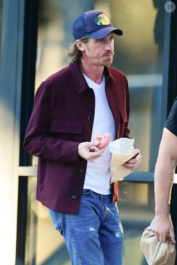 Exclusif - Garrett Hedlund ("Tulsa King") mange un Donuts en se promenant avec un ami à Los Angeles, le 3 décembre 2022.