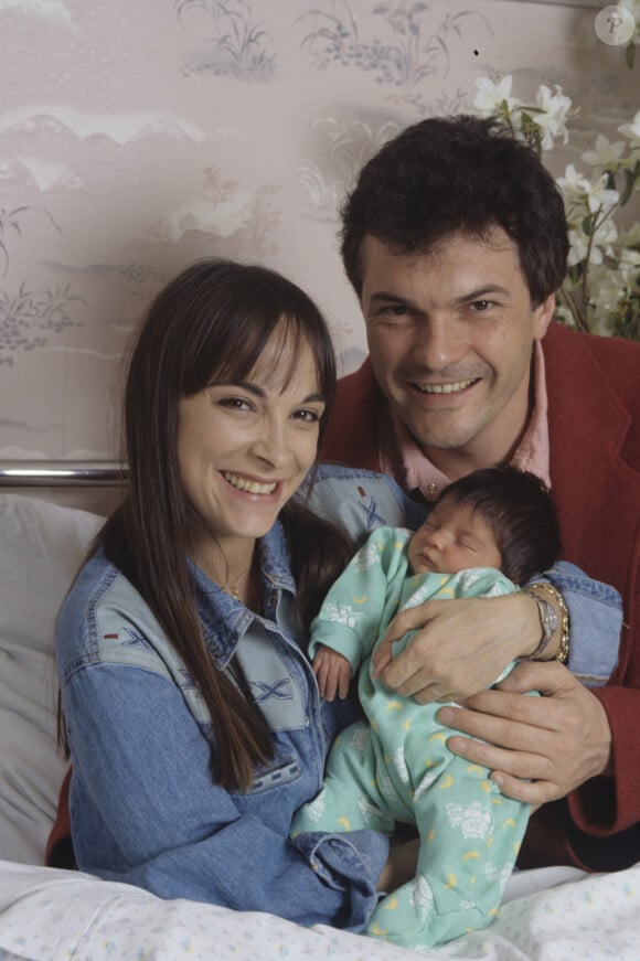 En France, à Paris, Ariane Carletti tenant dans ses bras sa fille Éléonore, dans sa chambre de la maternité avec à ses côtés son mari Rémy Sarrazin, membre du groupe LES MUSCLES le 31 mars 1994