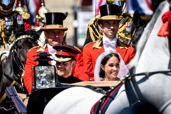 "Harry était en colère contre nous à cause des choses dites à propos de Meghan... Certaines choses étaient assez dures", a reconnu Arthur Edwards. "D'autres étaient plutôt injustes. Il était en colère et j'ai senti que nous étions punis pour cela".
Le prince Harry, duc de Sussex, et Meghan Markle, duchesse de Sussex, en calèche à la sortie du château de Windsor après leur mariage le 19 mai 2018 