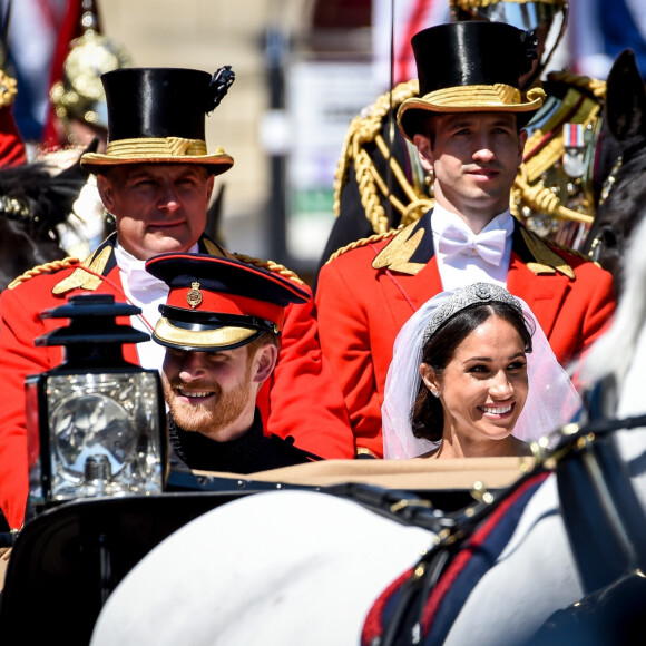 "Harry était en colère contre nous à cause des choses dites à propos de Meghan... Certaines choses étaient assez dures", a reconnu Arthur Edwards. "D'autres étaient plutôt injustes. Il était en colère et j'ai senti que nous étions punis pour cela".
Le prince Harry, duc de Sussex, et Meghan Markle, duchesse de Sussex, en calèche à la sortie du château de Windsor après leur mariage le 19 mai 2018 