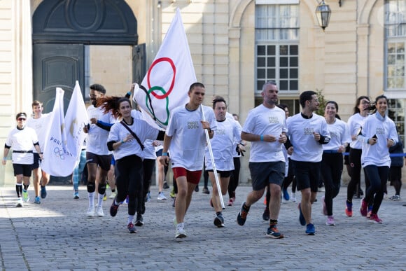 Les participants au Marathon Pour Tous arrivent avec les drapeaux des Jeux Olympiques et Paralympiques de Paris 2024 lors de la Tournée des drapeaux des Jeux Olympiques à l'Hôtel de Matignon à Paris le 25 avril 2024. Raphael Lafargue/Pool/Bestimage