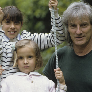 En France, Hugues Aufray avec ses petits-enfants, Emilie, 10 ans en arrière-plan, Joséphine, 4 ans, assise sur une balançoire, chez lui, dans sa maison de Marnes-la-Coquette