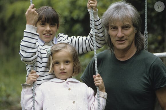 En France, Hugues Aufray avec ses petits-enfants, Emilie, 10 ans en arrière-plan, Joséphine, 4 ans, assise sur une balançoire, chez lui, dans sa maison de Marnes-la-Coquette