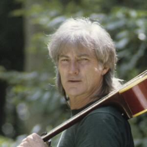 Hugues Aufray - En France, Hugues AUFRAY posant en extérieur, sa guitare sur l'épaule, chez lui, dans sa maison de Marnes-la-Coquette