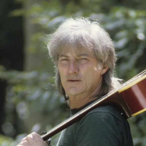 Hugues Aufray - En France, Hugues AUFRAY posant en extérieur, sa guitare sur l'épaule, chez lui, dans sa maison de Marnes-la-Coquette