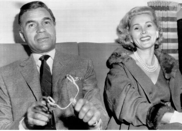 Le playboy-diplomate dominicain Porfirio Rubirosa s'amuse à viser le caméraman avec un lance-pierre alors qu'il s'apprête à décoller de l'aéroport international de Los Angeles pour New York en compagnie de l'actrice Zsa Zsa Gabor. Mlle Gabor se rendra bientôt à Paris pour y tourner un film. Les ambitions de Rubirosa à l'écran ont été récemment réduites à néant par le gouvernement américain qui lui a refusé un permis de travail pour tourner un western avec Mlle Gabor. 8 septembre, septembre 1955. Photo par Starstock/Photoshot/ABACAPRESS.COM