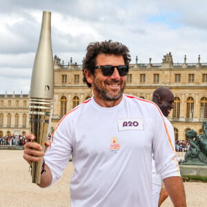 Le chanteur et acteur Patrick Bruel porteur de la flamme olympique des Jeux Olympiques de Paris 2024 (JO) au château de Versailles dans les Yvelines, France, le 23 juillet 2024. © Dominique Jacovides/Bestimage 