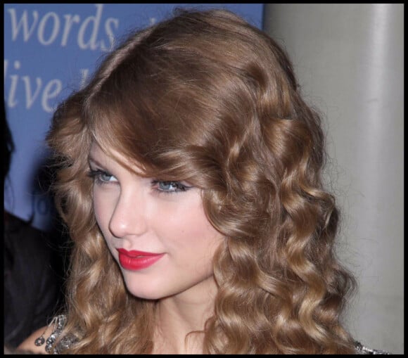 L'angélique Taylor Swift porte un rouge clair qui souligne ses cheveux blonds.