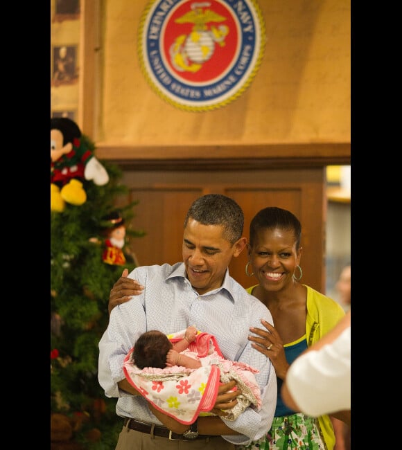 Barack et Michelle Obama visitant une base de la marine nationale le 25 décembre 2011 à Hawaï : en portant un bébé de militaire, le couple offre une photo superbe