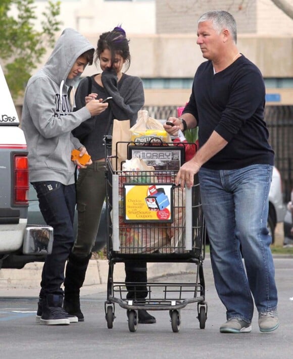 Justin Bieber et Selena Gomez, toujours bien surveillés par leur bodyguard, font leurs courses dans un supermarché de Los Angeles, le 14 janvier 2012.
