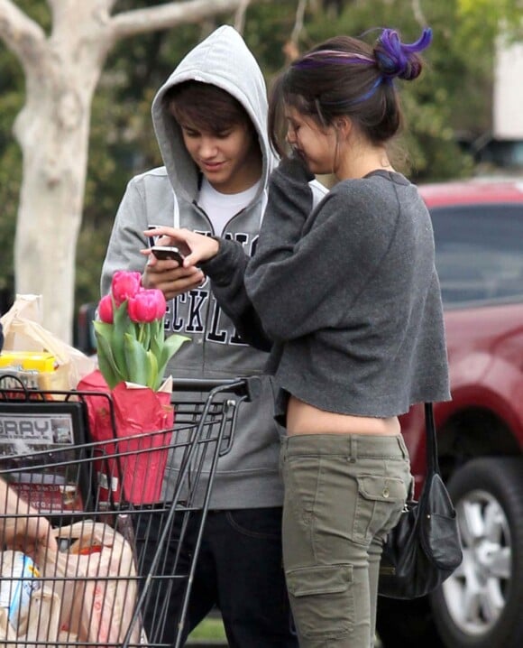 Petit moment de complicité avant de remplir le coffre de la voiture : Justin Bieber et Selena Gomez ont fait leurs courses dans un supermarché de Los Angeles, le 14 janvier 2012.