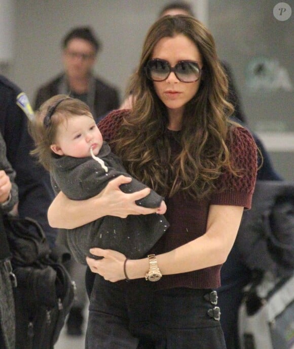Victoria Beckham et Harper, qui a mal digéré son biberon, à leur arrivée à l'aéroport de New York, le 7 février 2012.