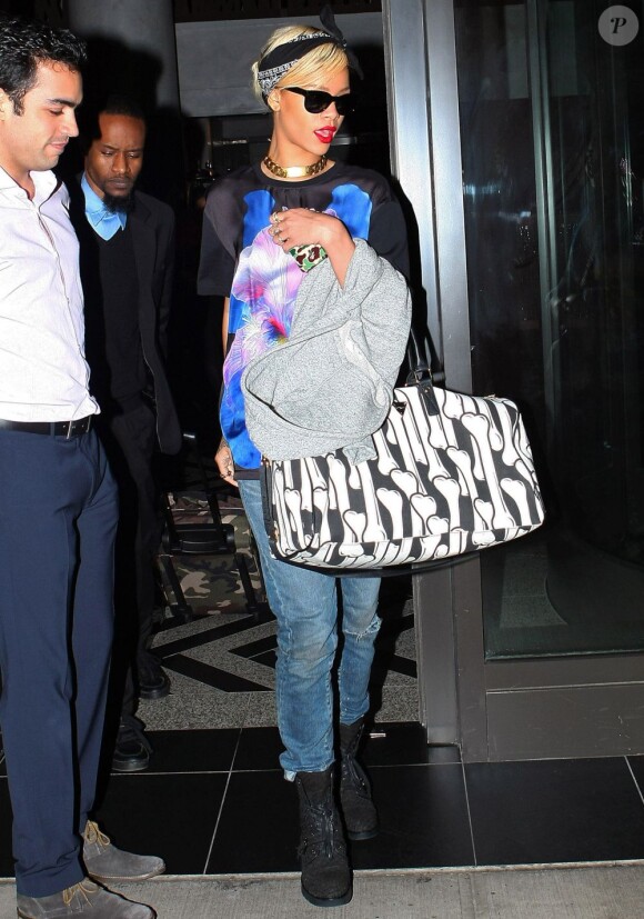 Rihanna quitte son hôtel pour se rendre à l'aéroport JFK de New York. La chanteuse porte un t-shirt Givenchy sur un jean assez large, des bottes noires Alexander Wang et un sac Joyrich. Le 18 mars 2012.