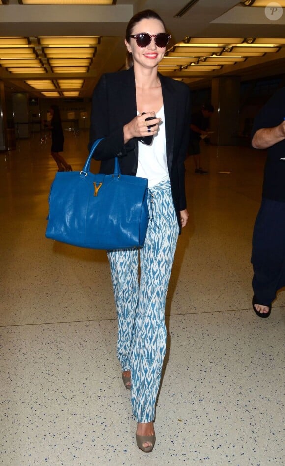 Miranda Kerr porte des lunettes Stella McCartney, un blazer Dior Homme sur un débardeur noir, un pantalon Joie, des souliers Christian Louboutin et un sac bleu azur Yves Saint Laurent à l'aéroport de Los Angeles. Le 12 juin 2012.