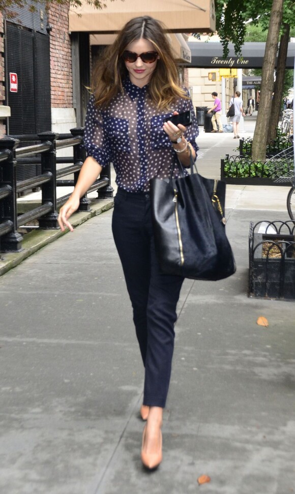 Miranda Kerr porte des lunettes Prada, un chemisier Equipment, un pantalon bleu marine et des escarpins Lanvin. Avec un sac Céline au bras, la belle Australienne illuminait New York. Le 13 juin 2012.