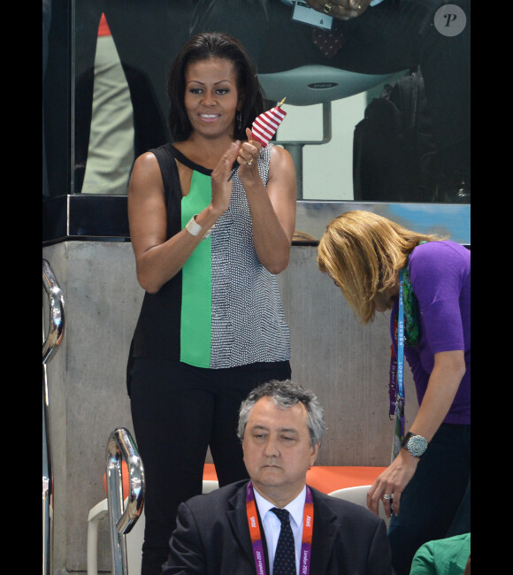 Drapeau à la main, Michelle Obama soutient les nageurs américains aux épreuves de natation, au parc aquatique, situé dans le Parc olympique à Stratford (Londres), le samedi 28 juillet 2012.