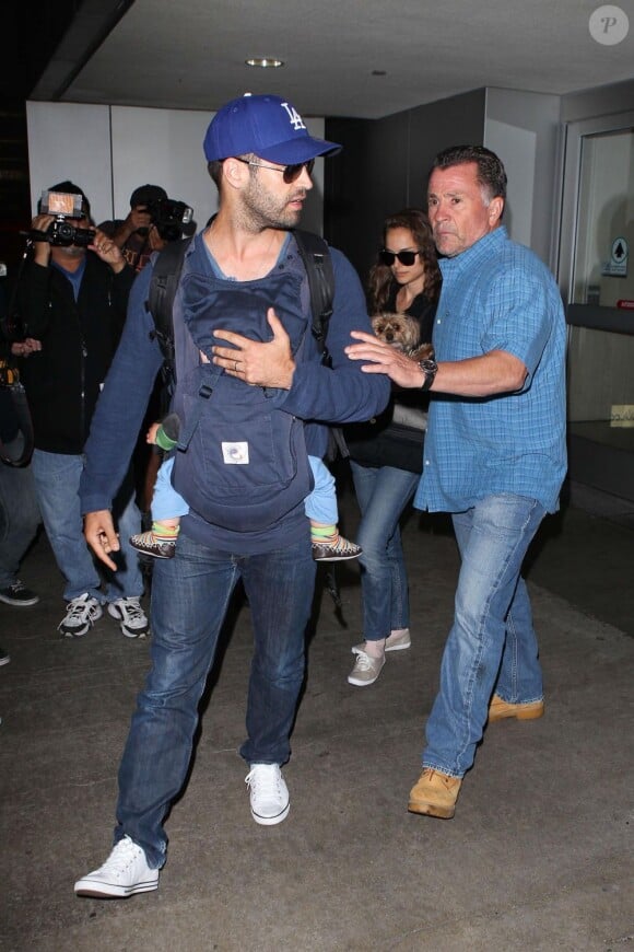 Benjamin Millepied protège son fils Aleph des photographes lors de son arrivée à Los Angeles. Le 29 juillet 2012