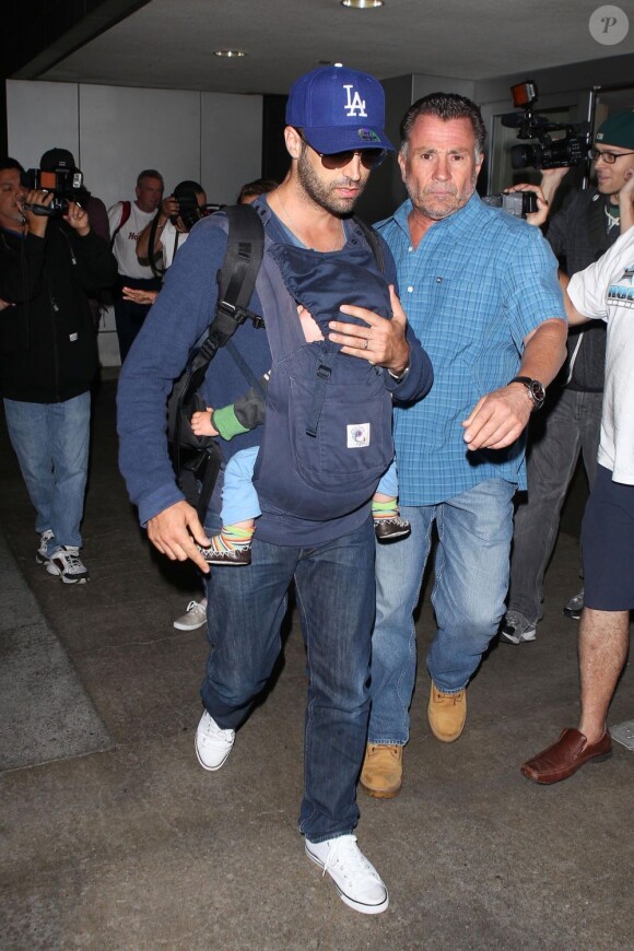 Benjamin Millepied tente de faire profil bas et protège son fils Aleph des photographes lors de son arrivée à Los Angeles. Le 29 juillet 2012