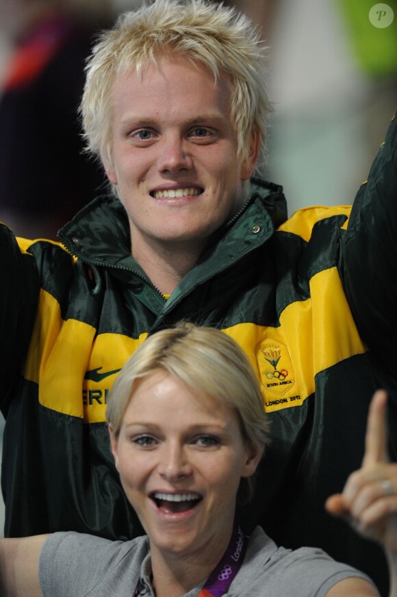 La princesse Charlene de Monaco aux Jeux olympiques de Londres 2012, à fond derrière les nageurs de l'Afrique du Sud.
