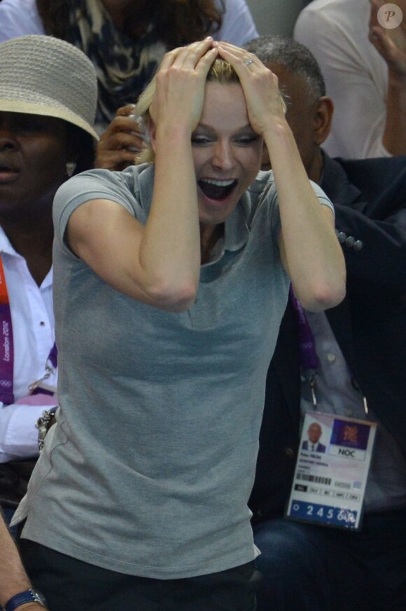 La princesse Charlene de Monaco aux Jeux olympiques de Londres 2012, à fond derrière les nageurs de l'Afrique du Sud.