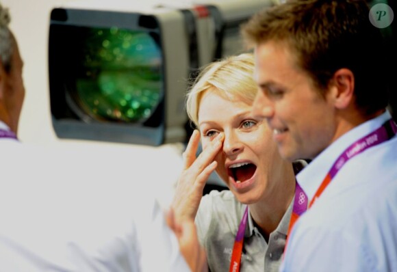 La princesse Charlene de Monaco aux Jeux olympiques de Londres 2012, à fond derrière les nageurs de l'Afrique du Sud.