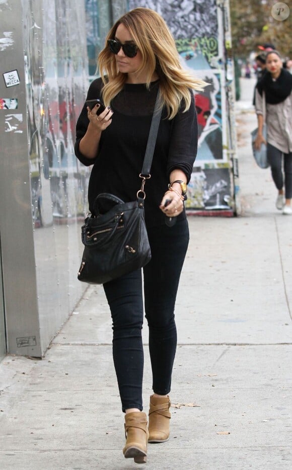 Lauren Conrad durant une séance shopping dans la boutique Urban Outfitters à West Hollywood, porte un sac Balenciaga en bandoulière sur un sweater et un jean slim noir. Des bottines marrons achèvent son look. Le 8 novembre 2012.