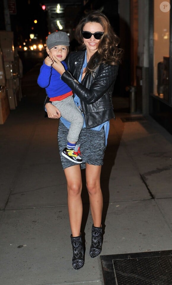 Miranda Kerr souriante avec son fils Flynn (1 an) dans les bras, porte une veste Balenciaga sur une chemise en jean, une mini-jupe Alexander Wang et des bottines Isabel Marant. New York, le 16 novembre 2012.