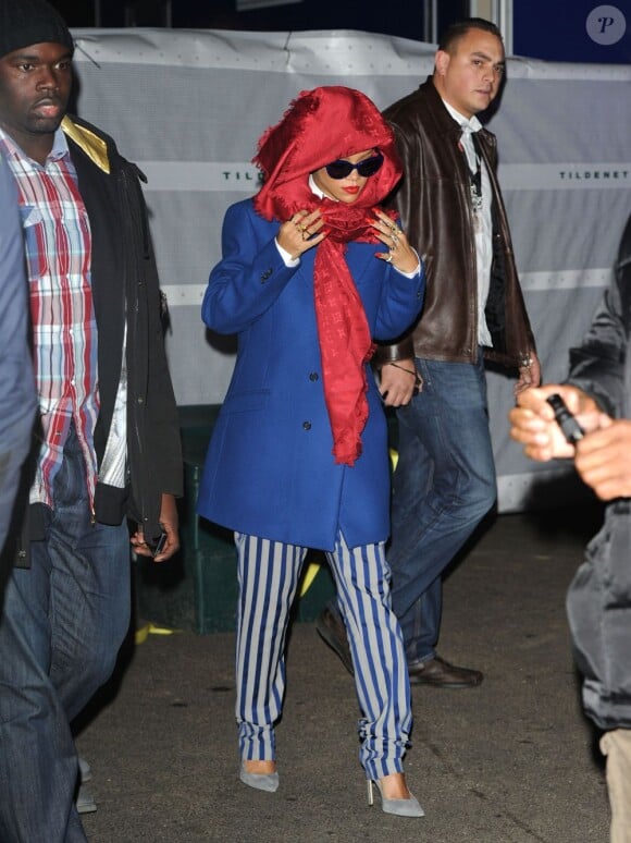 Rihanna à son arrivée au entre commercial Westfield Stratford City, se couvre la tête avec un foulard Louis Vuitton et porte un manteau Raf Simons, un ensemble Acne et des souliers Manolo Blahnik. Londres, le 19 novembre 2012.