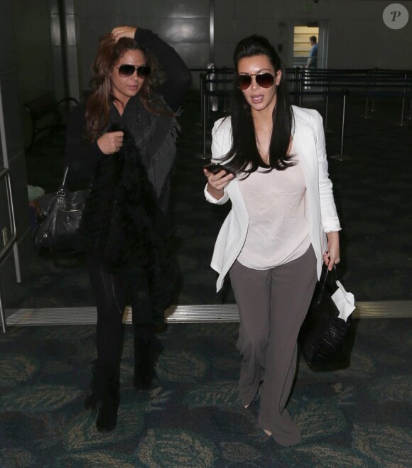 Kim Kardashian, enceinte, arrive à l'aéroport de Miami, le 6 janvier 2013. La star de la télé-réalité dévoile les premiers signes de sa grossesse. Elle est accompagnée d'une amie.