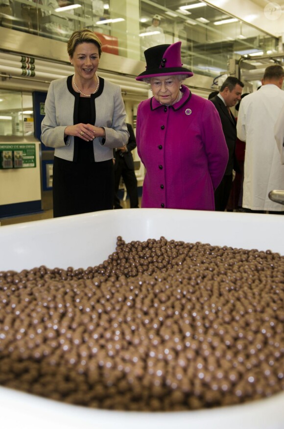 La reine Elizabeth II visite l'usine de fabrication des barres chocolatées Mars à Slough le 5 avril 2013 avec le duc d'Edimbourg.