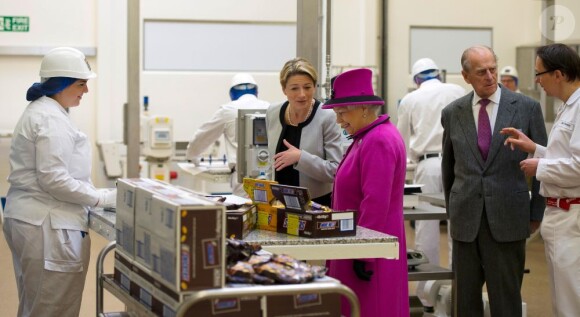 Elizabeth II visite l'usine de fabrication Mars à Slough le 5 avril 2013 avec son époux le duc d'Edimbourg.