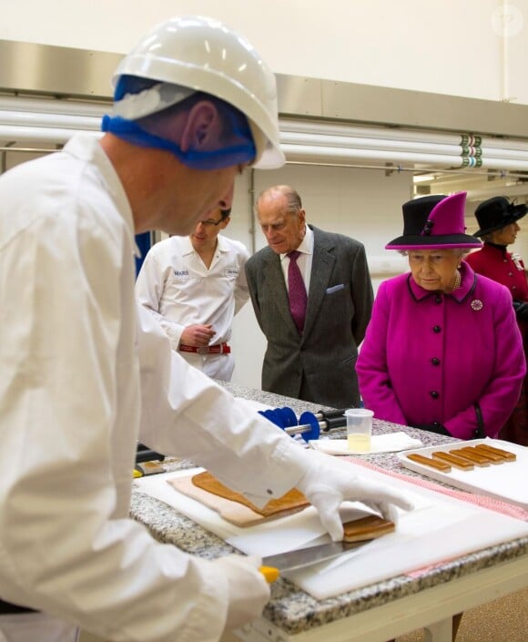 Elizabeth II visite l'usine de fabrication de Mars à Slough le 5 avril 2013 avec son époux le duc d'Edimbourg.