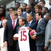Barack Obama et ses cadeaux reçus de l'équipe universitaire de football américain des Crimson Tide de l'Alabama le 15 avril 2013 à la Maison Blanche