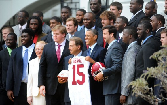 Barack Obama et ses cadeaux reçus de l'équipe universitaire de football américain des Crimson Tide de l'Alabama le 15 avril 2013 à la Maison Blanche