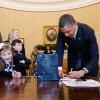 Le président Barack Obama signe des cartes pour l'association March of Dimes, devant sa jeune ambassadrice Nina Centofanti le 26 mars 2013 dans le bureau oval de la Maison Blanche