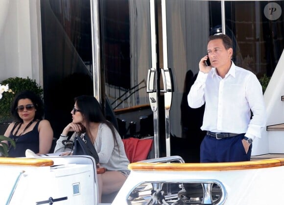 Eric Besson, au téléphone, et sa femme Yasmine se promenant sur la Croisette en plein Festival de Cannes le 23 mai 2013. Ils font escale sur un yacht luxueux