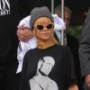 Rihanna quitte l'hôtel Lowry à Manchester, habillée d'un T-shirt à l'effigie de l'acteur Woody Harrelson dans le film Tueurs Nés (Natural Born Killers, 1994), avec un jean boyfriend et des sandales Saint Laurent. Un collier vintage Christian Lacroix et des lunettes Versace complètement son look. Le 13 juin 2013.