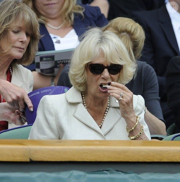 Camilla Parker Bowles, avale un petit-four dans les tribunes du All England Lawn Tennis and Croquet Club à Wimbledon le 27 juin 2013