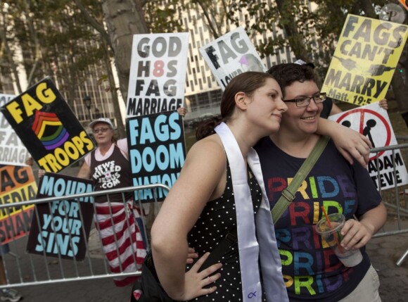 Un couple de lesbiennes pose courageusement devant les membres de la Westboro Baptist Church qui manifestent contre le mariage gay à New York, le 24 juillet 2011. 