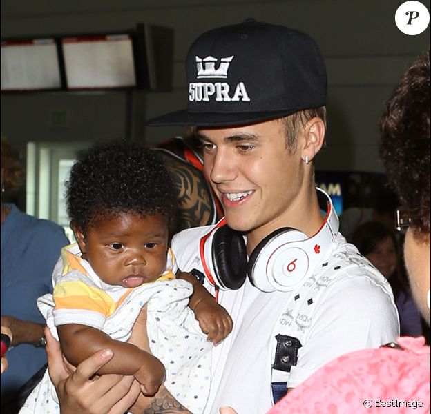 Justin Bieber attentionné avec un nourrisson, à l'aéroport de Fort Lauderdale, en Floride, le 16 août 2013.