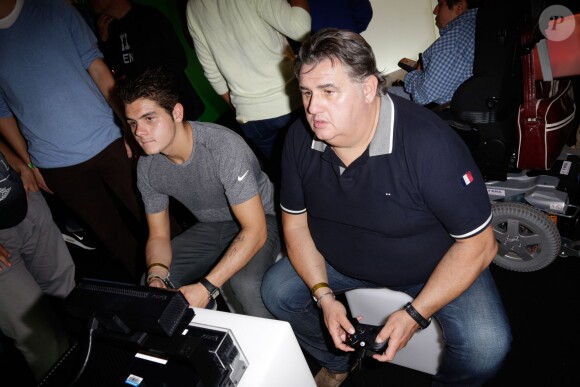 Pierre Ménès et son fils Axel en compétition à la soirée de lancement de FIFA 14, organisée à la Gaîté Lyrique, à Paris, le 23 septembre 2013. La simulation de foot d'EA Sports sort le 26 septembre.